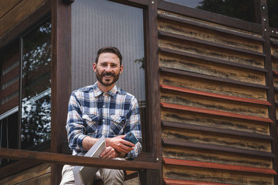 Portrait of smiling young man standing against wall
