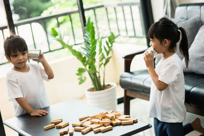 Cute sisters playing with tin can phone at home