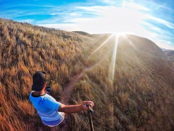 Rear view of man standing on land against sky