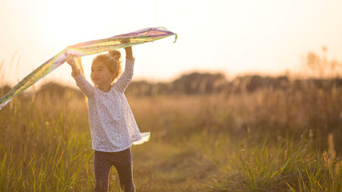 Girl holding kite standing on field