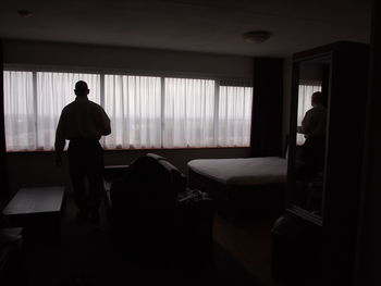 Rear view of man walking by sofa at home