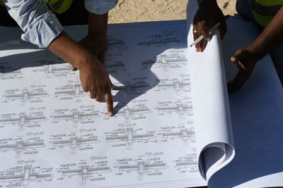 Midsection of architects looking at blueprint