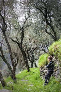 Side view of boy standing in forest