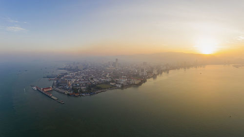 High angle view of sea and buildings against sky during sunset