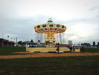 People at amusement park against cloudy sky