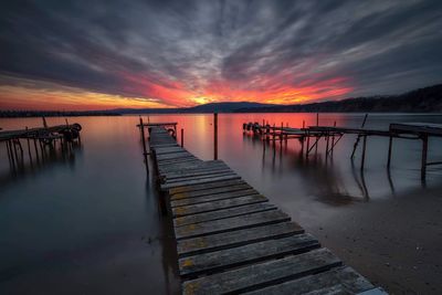 Pier over lake against sky during sunset