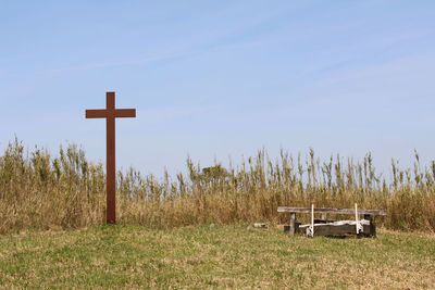 Cross on field against sky