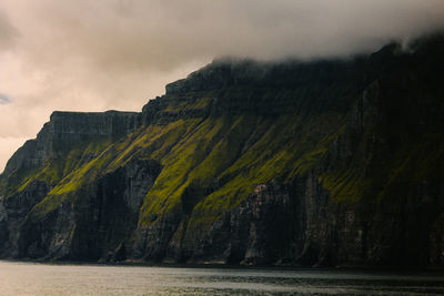 Scenic view of mountain by sea against sky