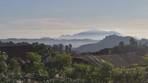 Houses on field by mountains against sky