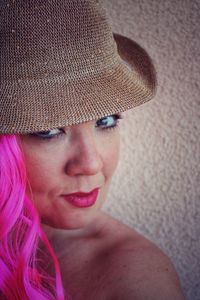 Close-up portrait of shirtless woman wearing wig against wall