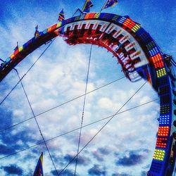 Low angle view of ferris wheel against cloudy sky