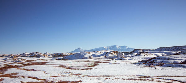 Scenic view of snowcapped mountains against clear blue sky