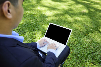 Midsection of man using mobile phone in field