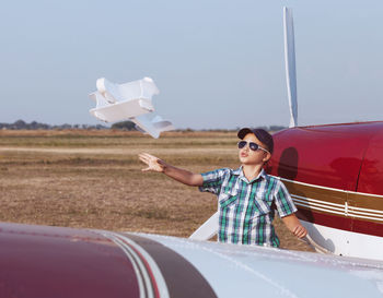 Boy wearing sunglasses while standing by car against sky