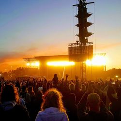 People enjoying at music concert against sky during sunset