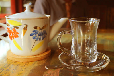 Closeup a transparent teacup with a porcelain teapot on the table