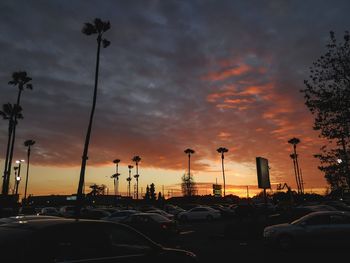 Cars on road against cloudy sky at sunset