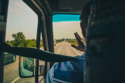 Man holding glass window against sky