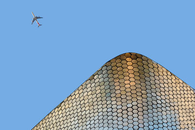 Low angle view of airplane flying against clear blue sky