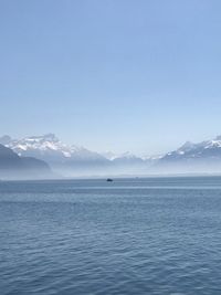 Scenic view of sea and snowcapped mountains against sky