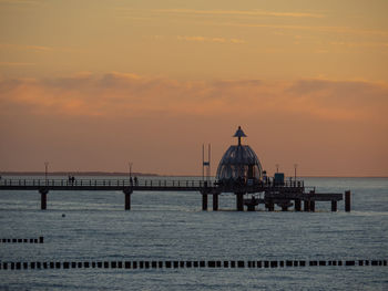 Pier over sea against sky during sunset