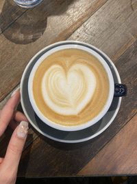 Cropped hand of person holding coffee on table