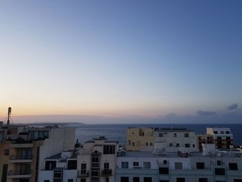 High angle view of townscape by sea against sunset sky