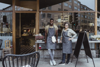 Portrait of smiling male and female coworker outside deli store