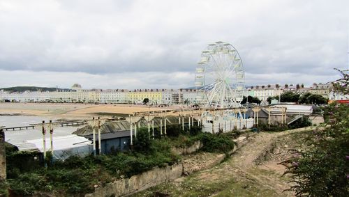 Ferris wheel by city against sky