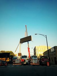 Cranes at construction site against clear blue sky
