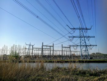 Low angle view of electricity pylon on field against sky
