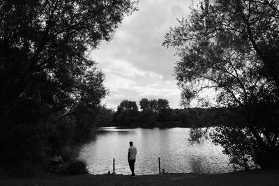 Men standing by lake against sky