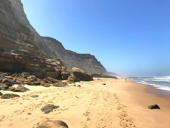 Scenic view of beach against clear blue sky