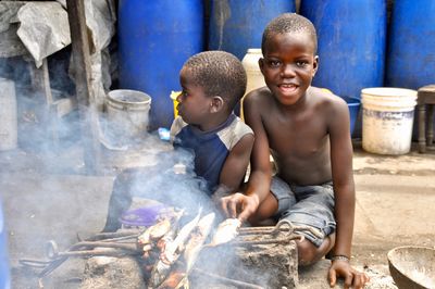 Two boys prepare fish on a grill