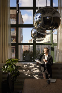 Portrait of young woman standing by window