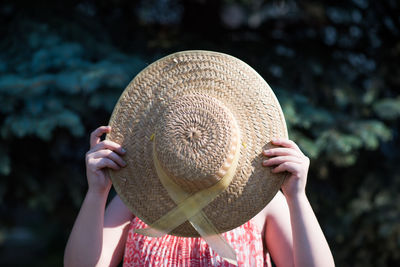 Woman holding sun hat on sunny day