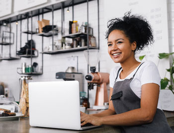Smiling woman using laptop at commercial kitchen
