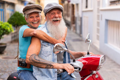 Front view of a modern senior couple riding on a motorcycle while driving through town