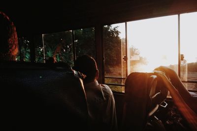 Man sitting in bus during sunset