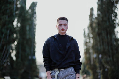 Portrait of young man standing against sky