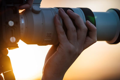 Cropped hand of a man holding a camera with a telephoto lens 