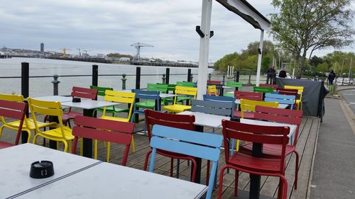 Empty chairs and tables against sky