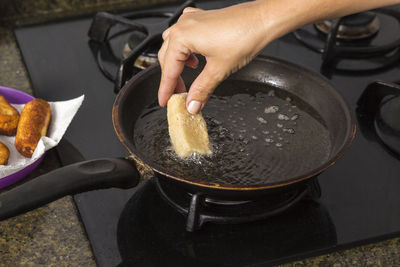 Cropped hand putting food in frying pan
