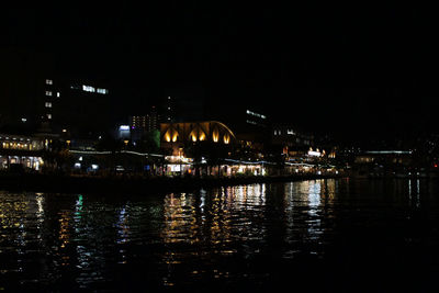 River by illuminated buildings in city at night