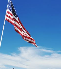 Low angle view of red flag against blue sky