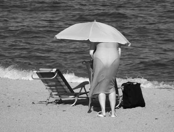 Rear view of woman with umbrella on shore at beach