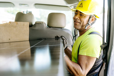 Smiling engineer holding solar panel in van