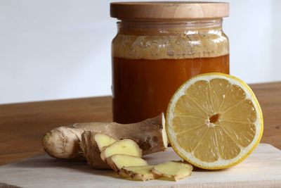 Close-up of honey in jar with ginger and halved lemon on table