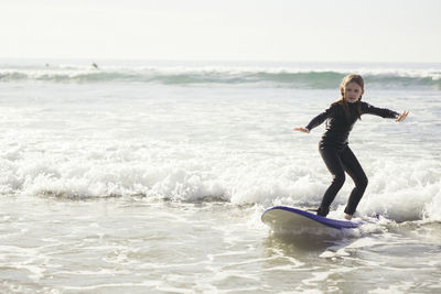 Full length of girl surfing in sea