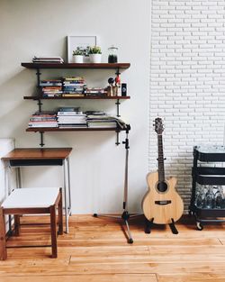 Acoustic guitar by shelf against wall at home